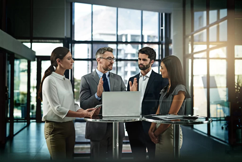 Team discussing a website project around a laptop in a bright office